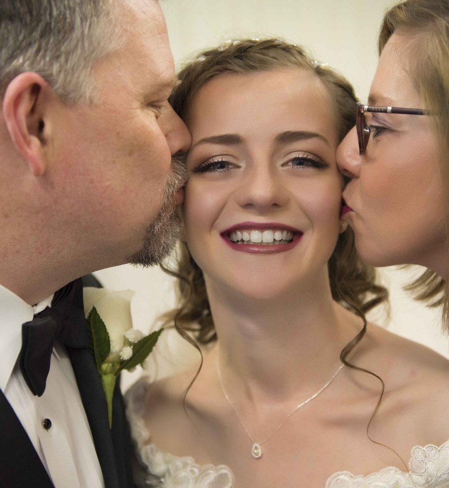 mom and dad kissing the bride